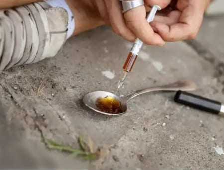 Употребление героина Шприц с коричневой жидкостью